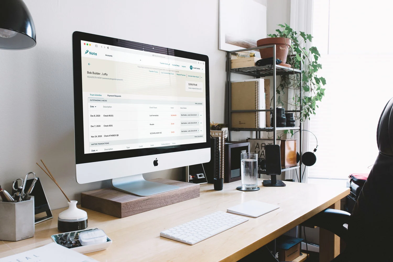 Nota platform shown on an iMac in a workspace — outstanding checks and matter-level activity in view.